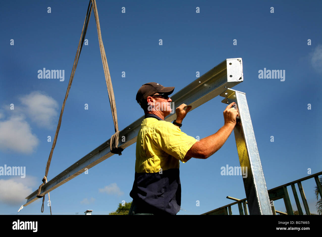 Un trabajador de la construcción coloca una viga de acero durante la construcción de una casa. Foto de stock