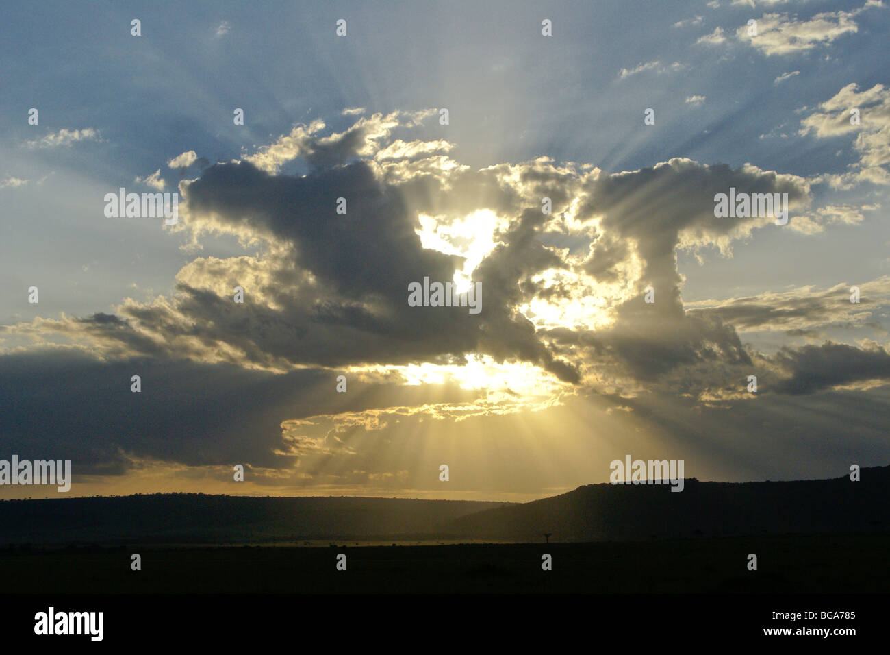 El sol detrás de las nubes (rayos crepusculares), Masai Mara, Kenya Foto de stock