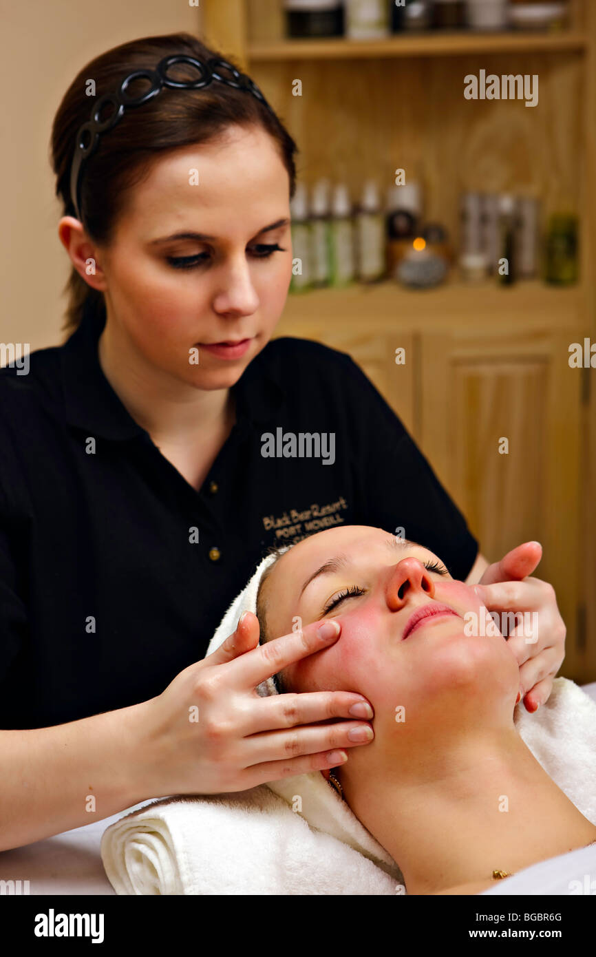 Una joven mujer recibiendo un masaje facial de un terapeuta durante un relajante tratamiento facial en el Oso Negro Resort & Spa, por Foto de stock