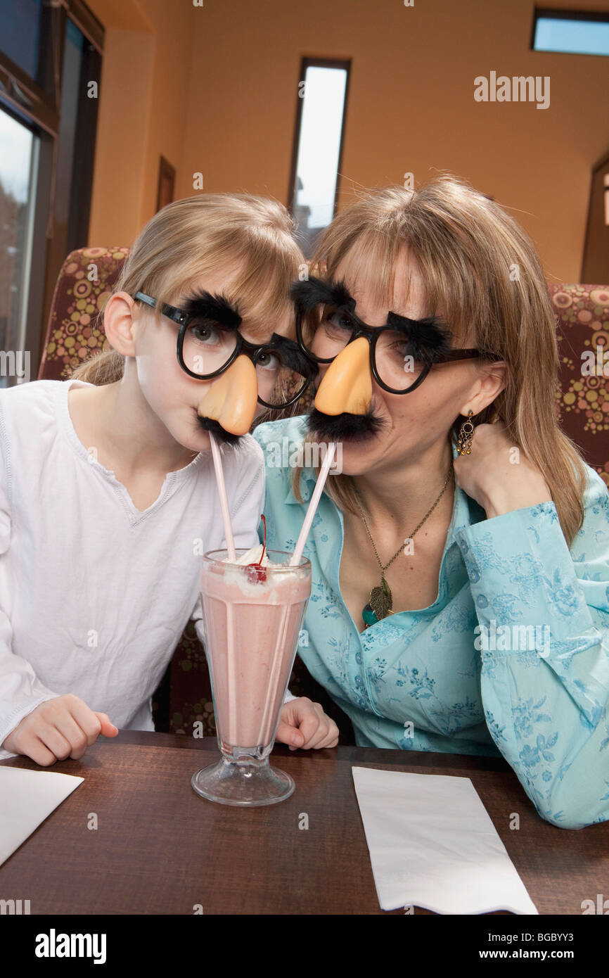 Madre e hija comparten milkshake en disfraz Foto de stock