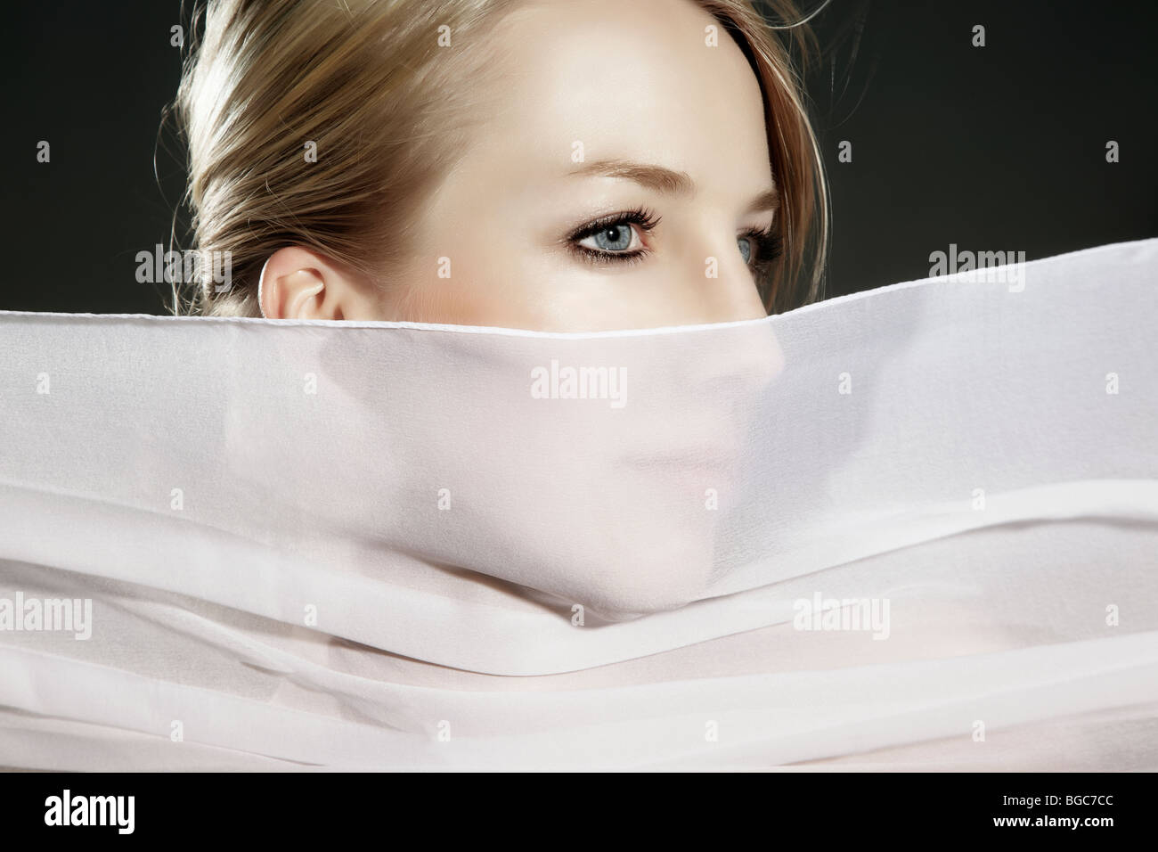 Retrato de una mujer joven con una tela de seda blanca que fluye delante de su rostro Foto de stock