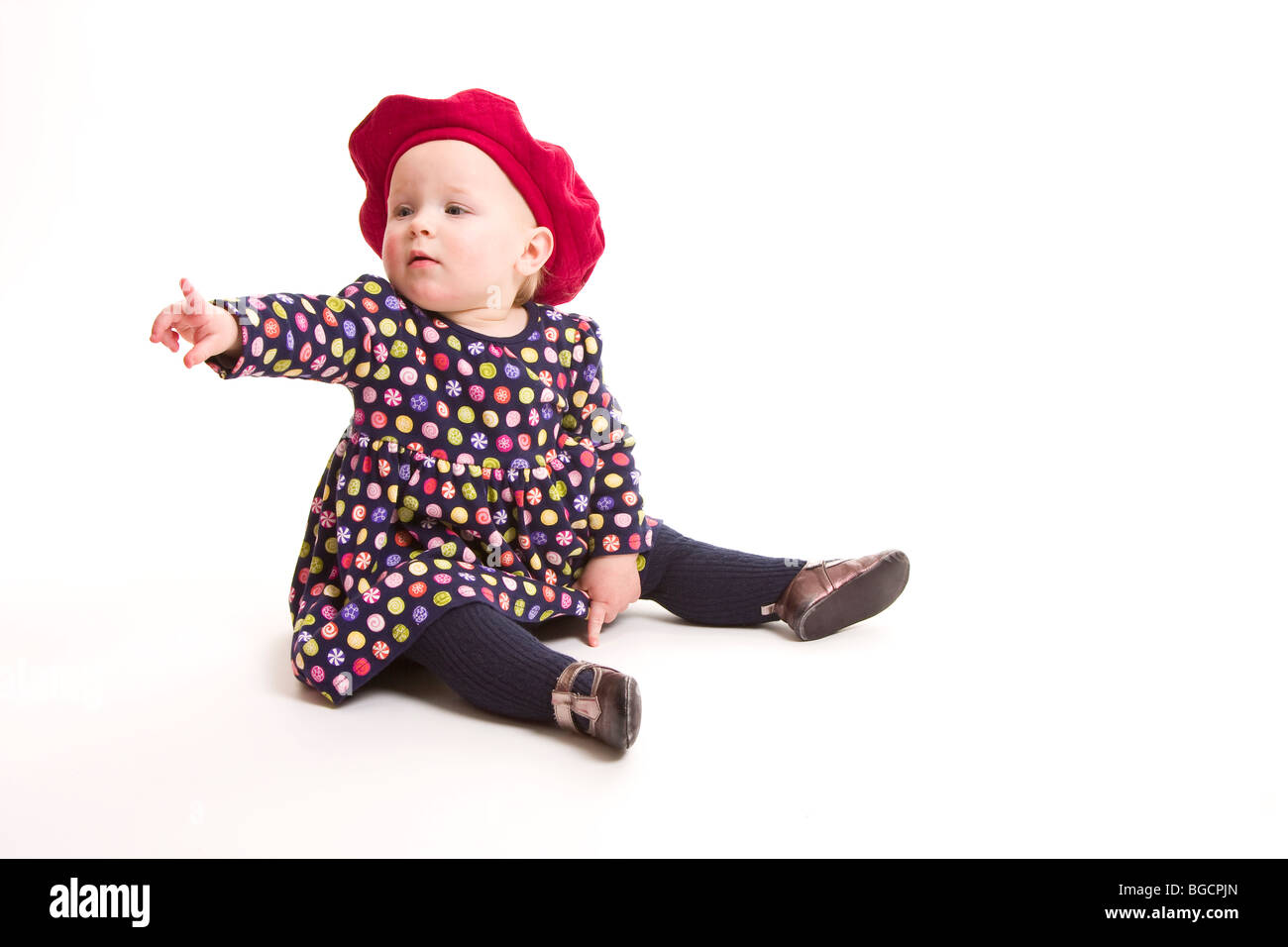 Niña de 1 año de edad en un boina roja puntos con su dedo aislado blanco Fotografía de stock - Alamy