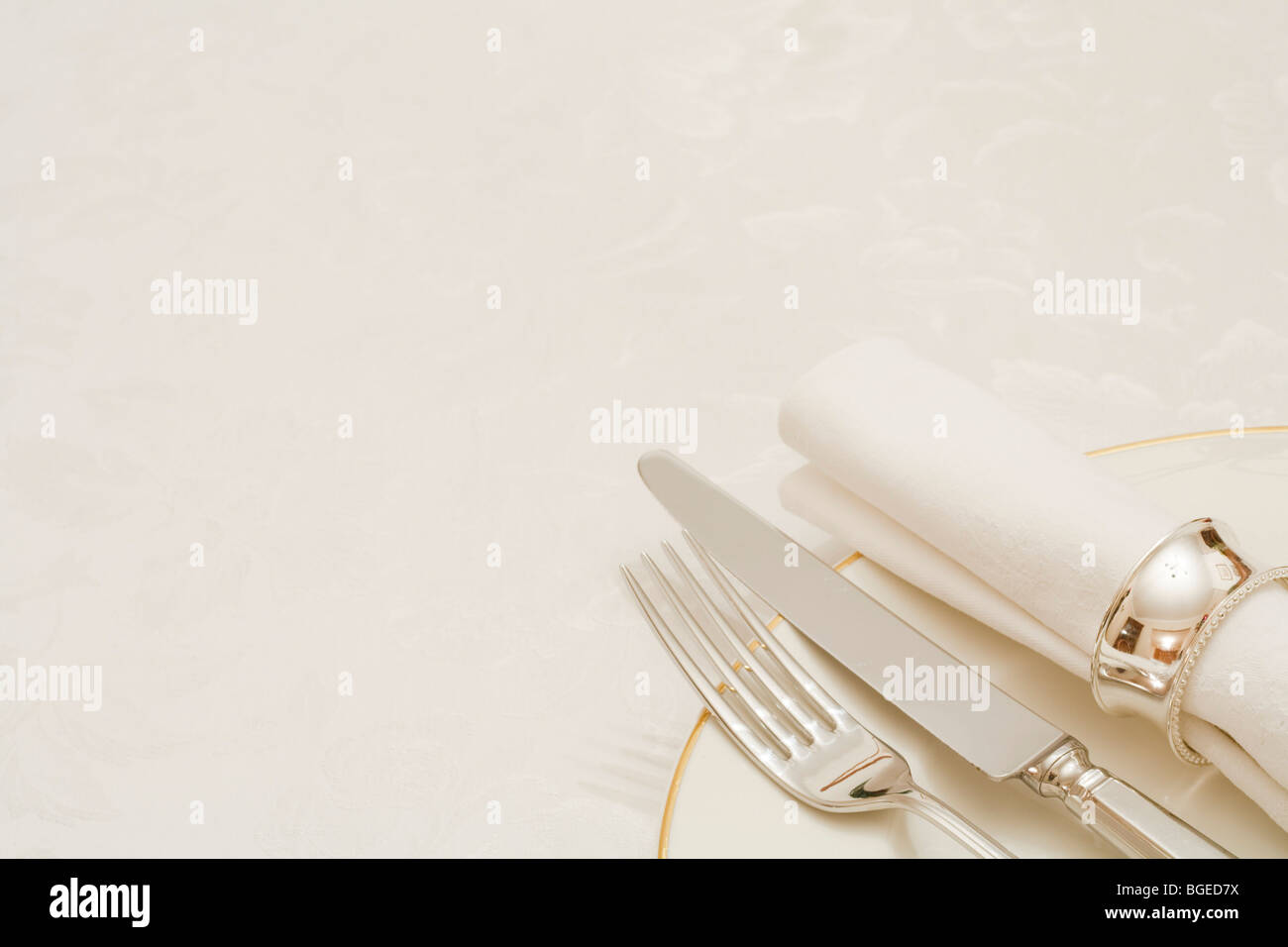 Cuchillo y tenedor con servilleta y placa, sobre un mantel con copyspace Foto de stock