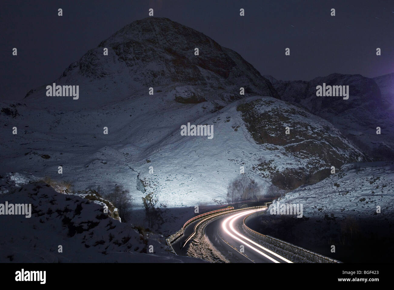 El tráfico se mueve a través del paso de Glencoe, Escocia, al caer la noche tras el final de las vacaciones de Navidad. Foto de stock
