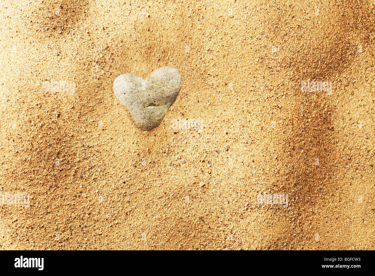 Piedra en forma de corazón en la arena Foto de stock
