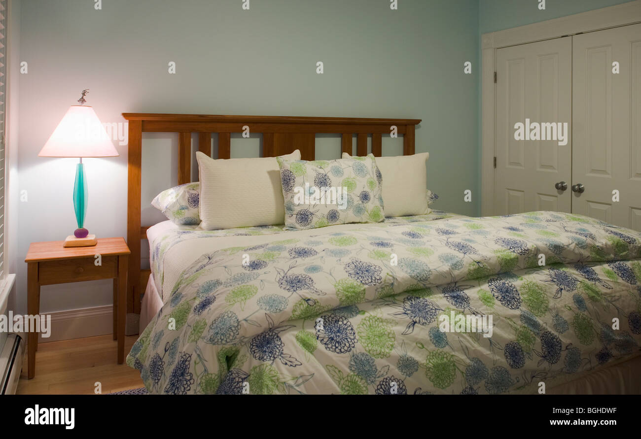 Cama matrimonial en el dormitorio con consolador azul y verde Foto de stock