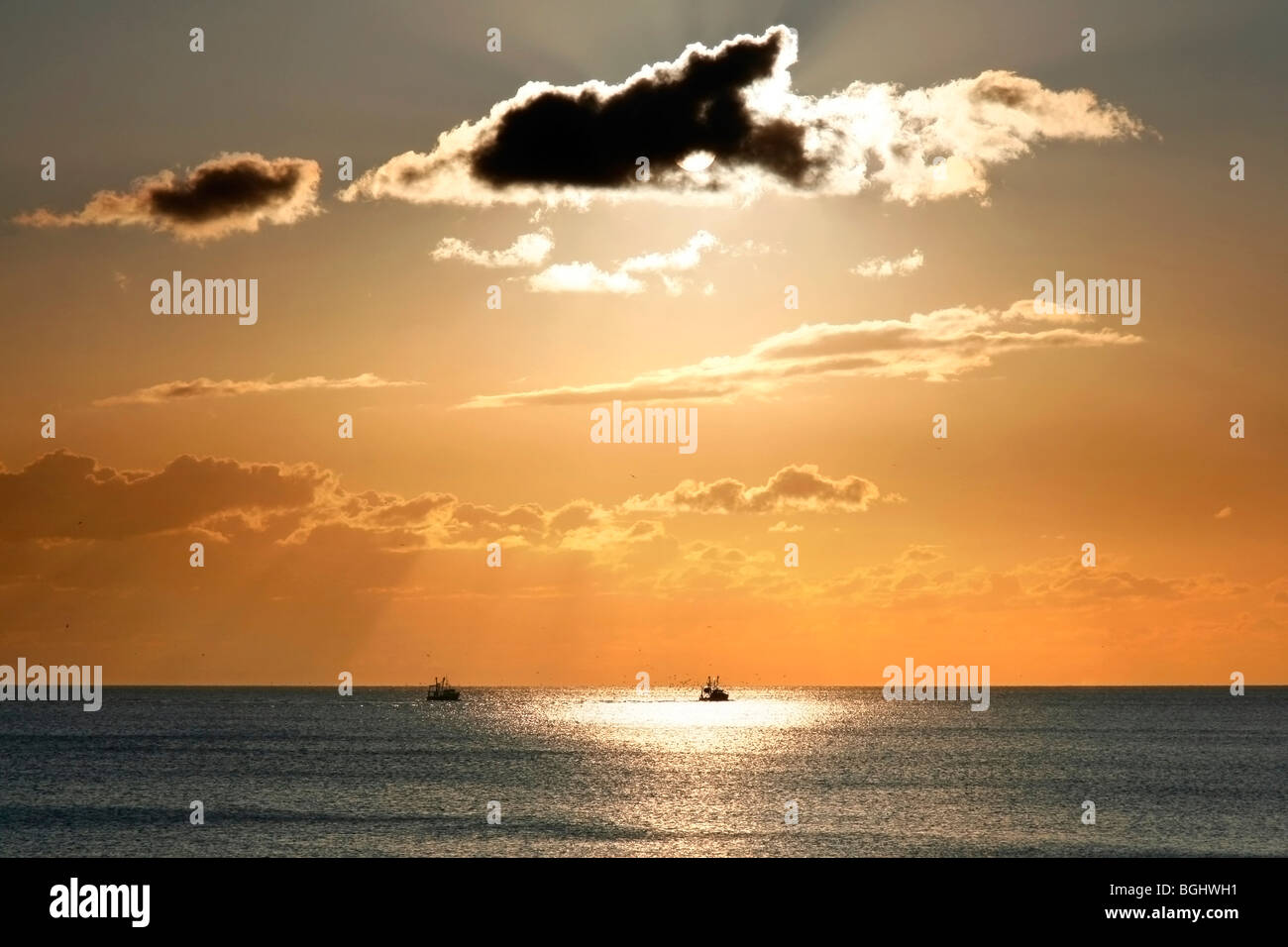 Los botes pesqueros en el horizonte bajo un cielo espectacular atardecer desde la playa de Brighton Foto de stock