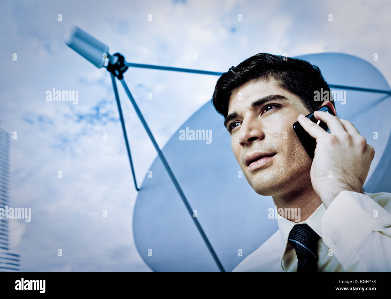 Un joven empresario en un teléfono móvil con antena parabólica en segundo plano. Foto de stock