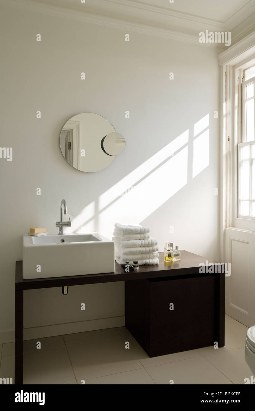 Moderno cuarto de baño con lavabo y espejo redondo negro Foto de stock