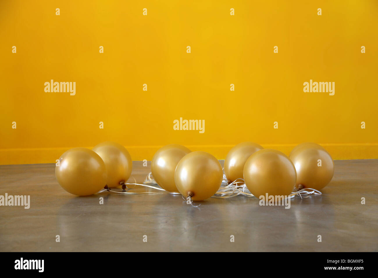 Los globos de oro se hunden en el suelo después de la fiesta, deflactado Foto de stock