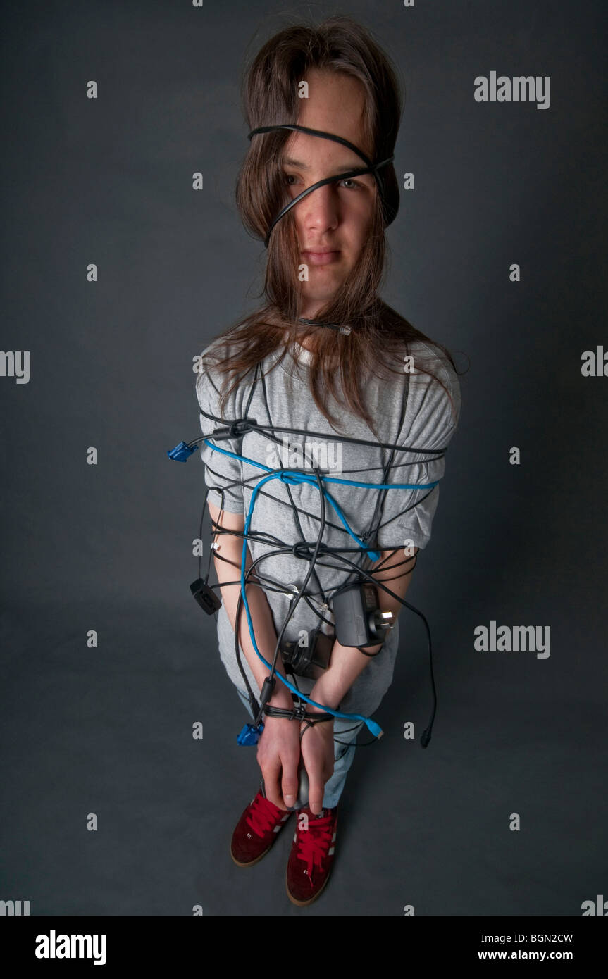 Adolescente con pelo largo atado con cables de computadora Foto de stock