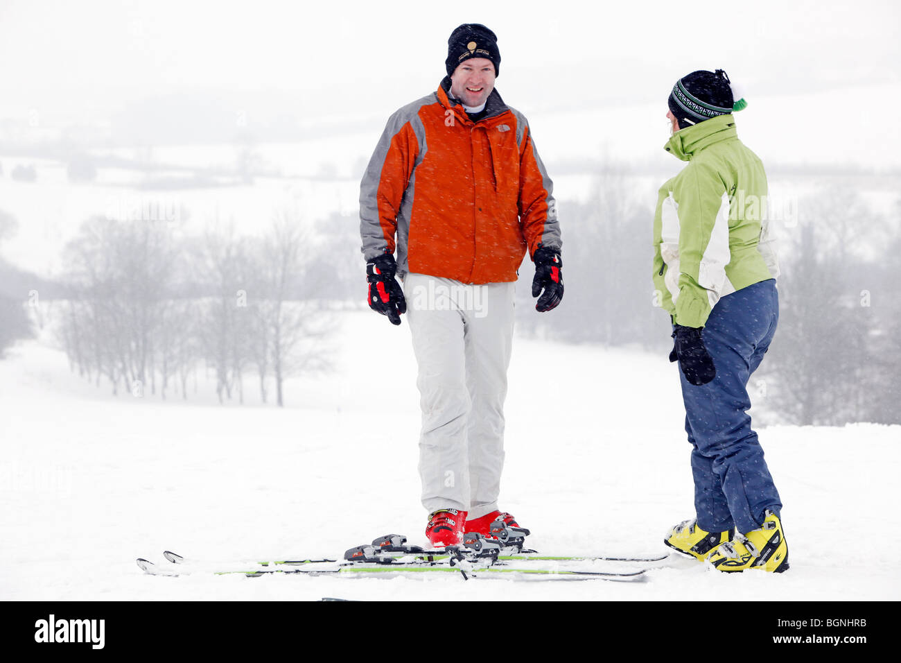 Dos un hombre y una mujer vestida con ropa de esquí, chatear en una ladera con Fotografía de - Alamy