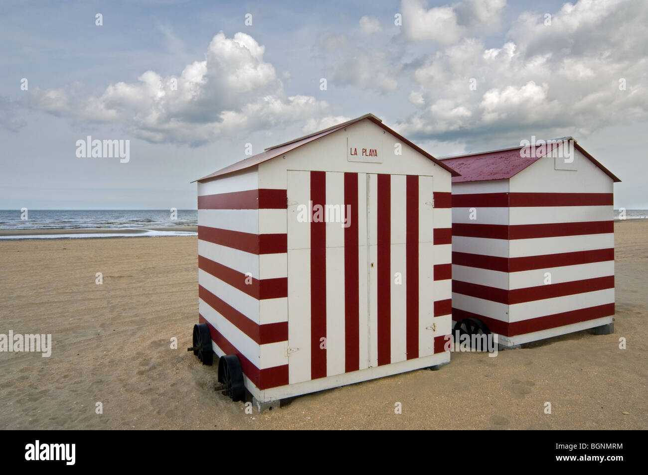 Fila de color rojizo con rayas blancas sobre ruedas cabañas de playa en la costa del Mar del Norte en De Panne, Bélgica Foto de stock