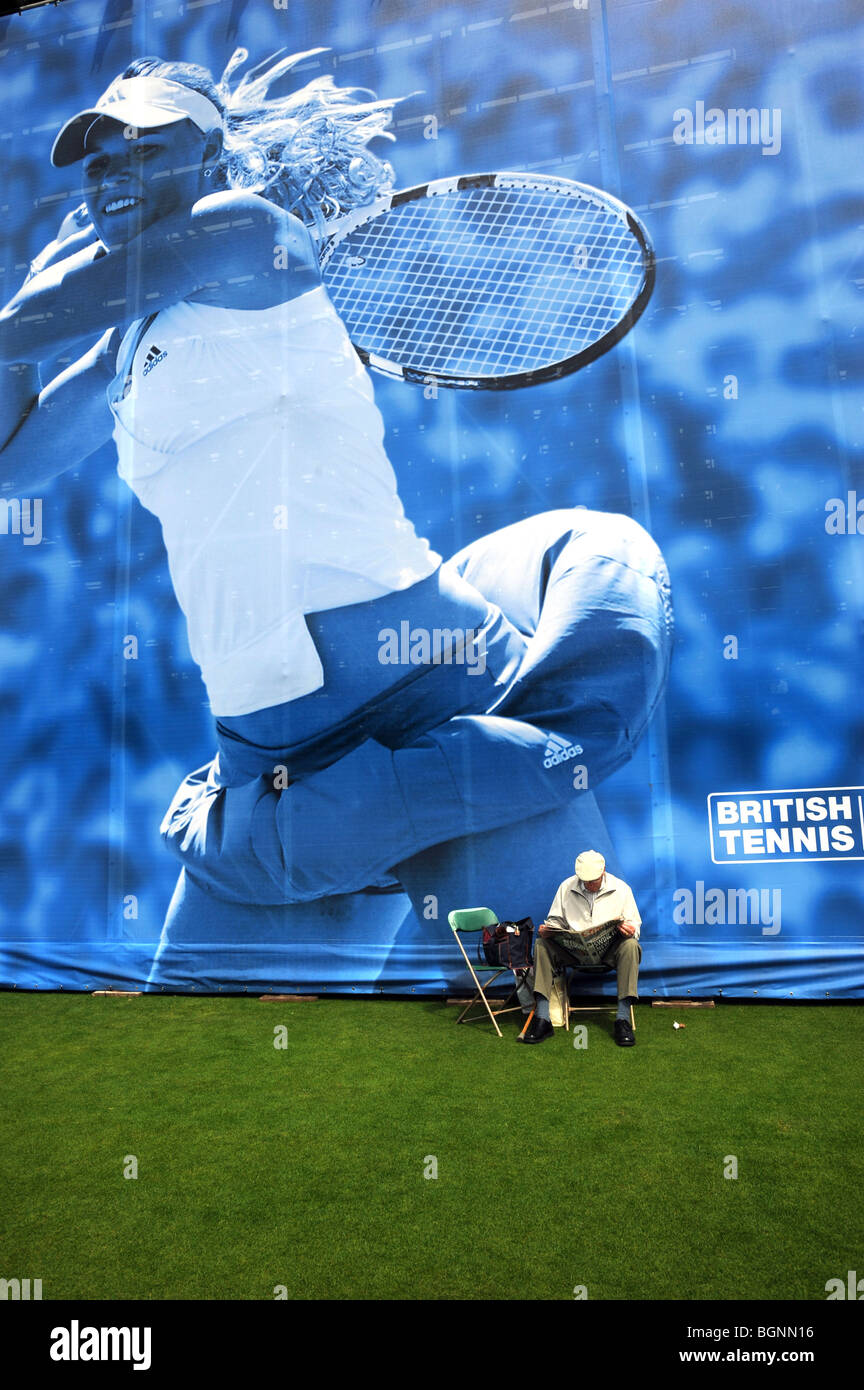 Un hombre lee un periódico junto al stand principal en el campeonato internacional de tenis aegon en Devonshire park eastbourne Foto de stock