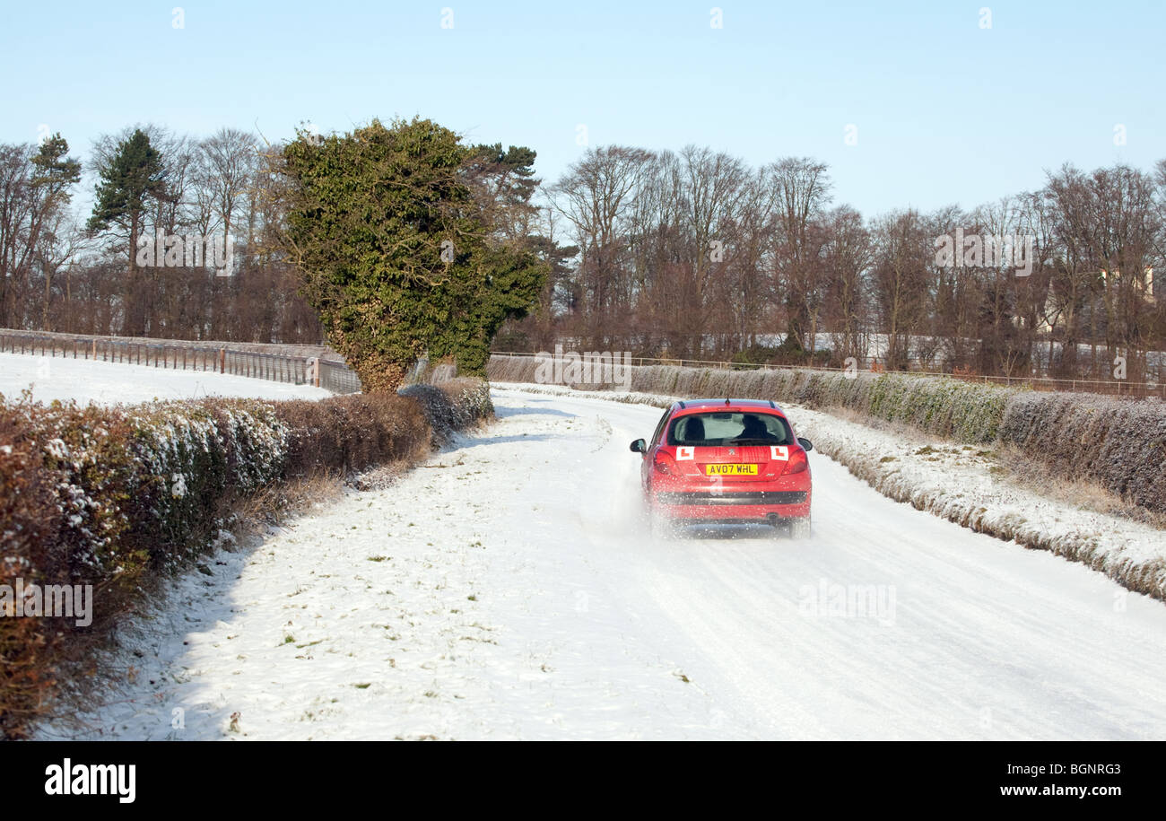 Un conductor principiante conducir en una carretera rural en nieve, Newmarket Suffolk UK Foto de stock