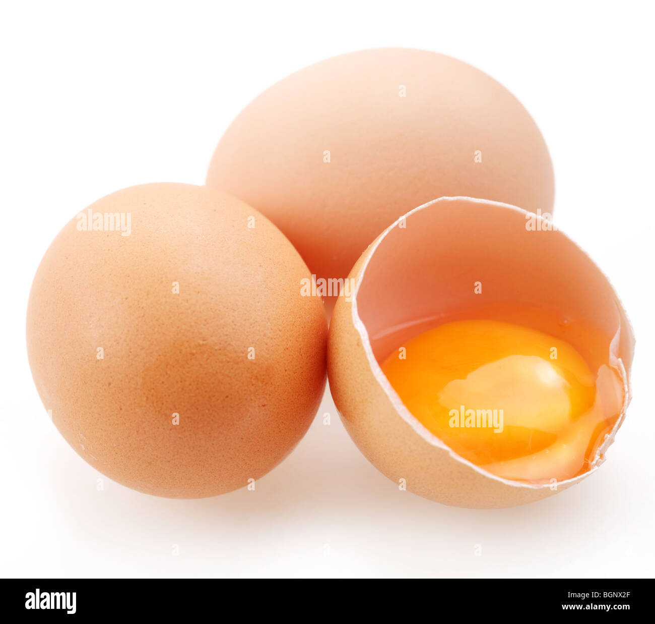 Con huevos marrón sobre un fondo blanco. Un huevo está roto. Foto de stock