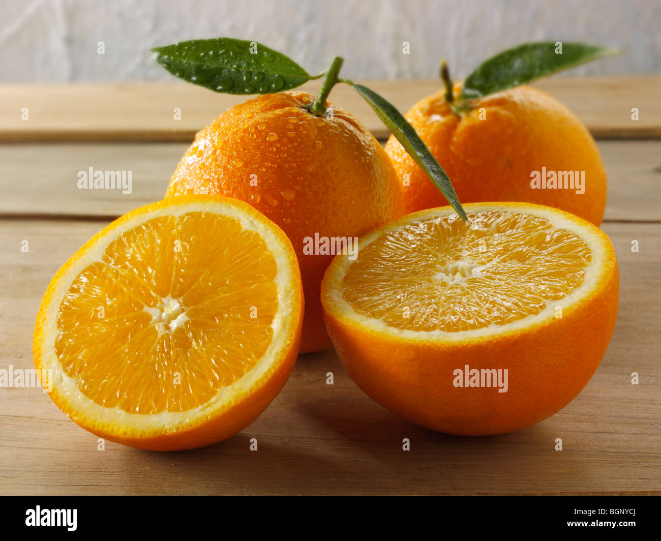 Todo y cortar naranjas frescas con hojas Foto de stock
