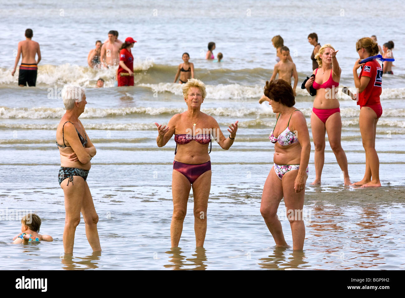 Las mujeres ancianas en bikinis remando a lo largo de la playa del Mar del  Norte en la ciudad balnearia durante el caluroso verano vacaciones  Fotografía de stock - Alamy