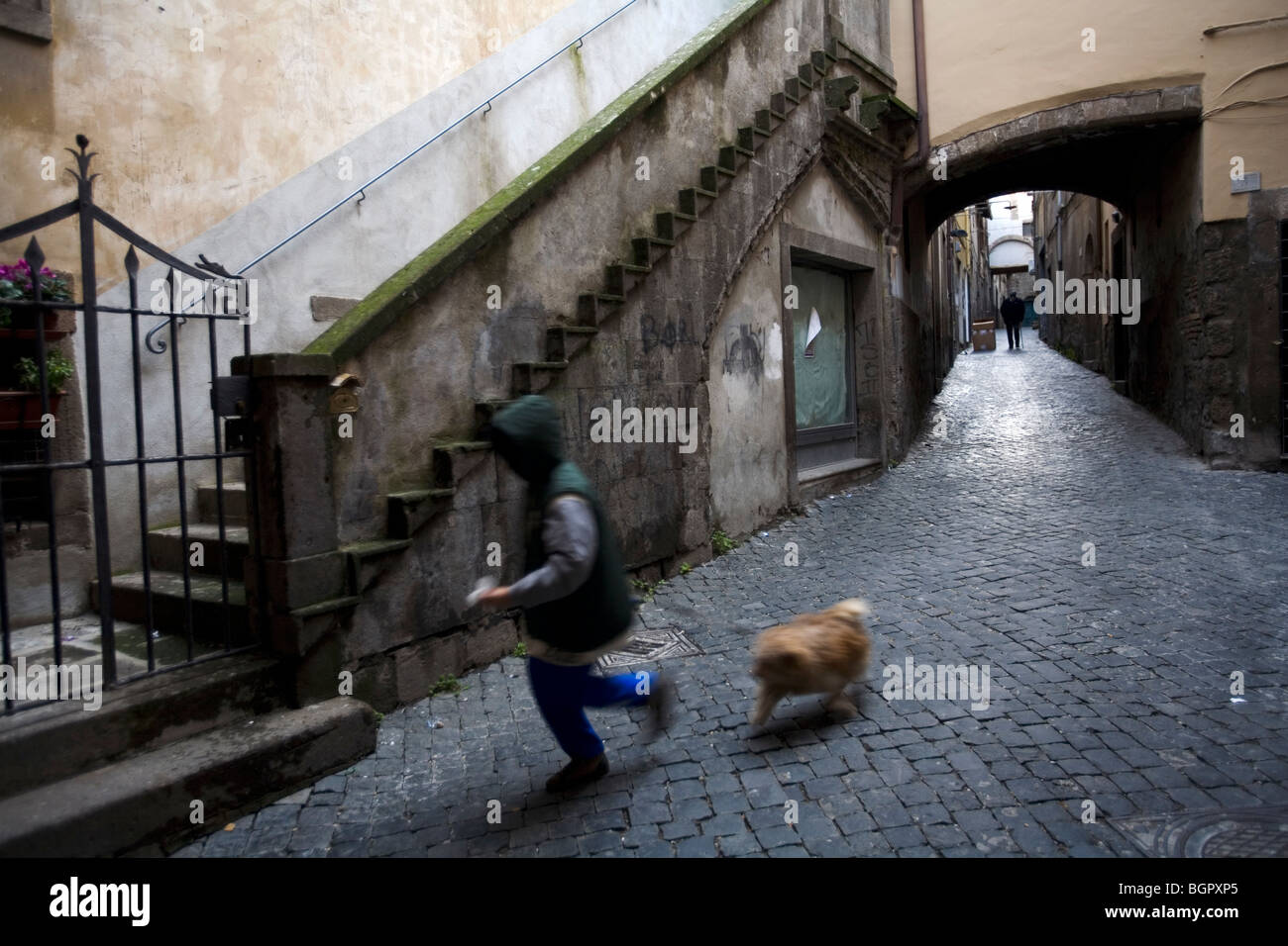 Pequeño niño corriendo con su perro en un callejón, Viterbo, Lacio, Italia. Foto de stock