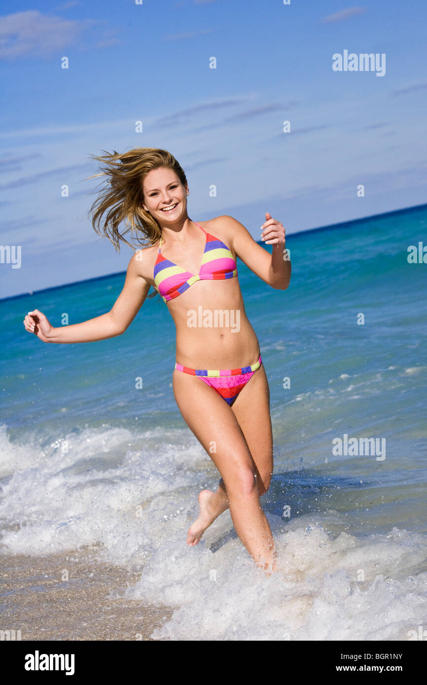 Hermosa hembra caucásica ejecutando a través de adolescentes para navegar  usando un bikini de colores Fotografía de stock - Alamy