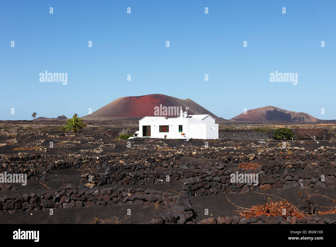 Casa Blanca en la región vinícola de La Geria, volcanes en la distancia, desde la izquierda, Caldera Colorada, Montaña Ortiz, Lanzarote, Cana. Foto de stock