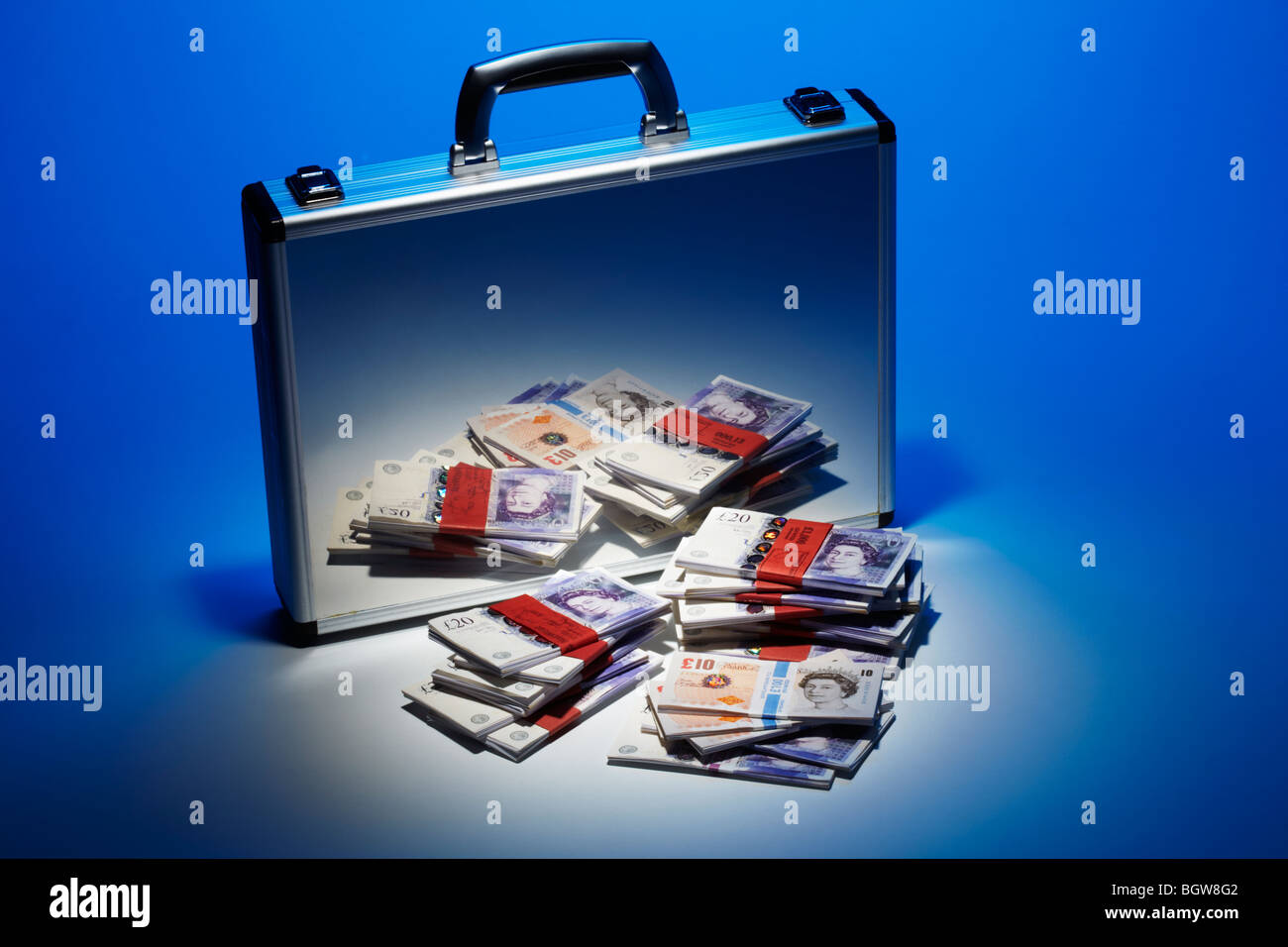 Los billetes de banco apilados reflejado en plata Maletín Foto de stock