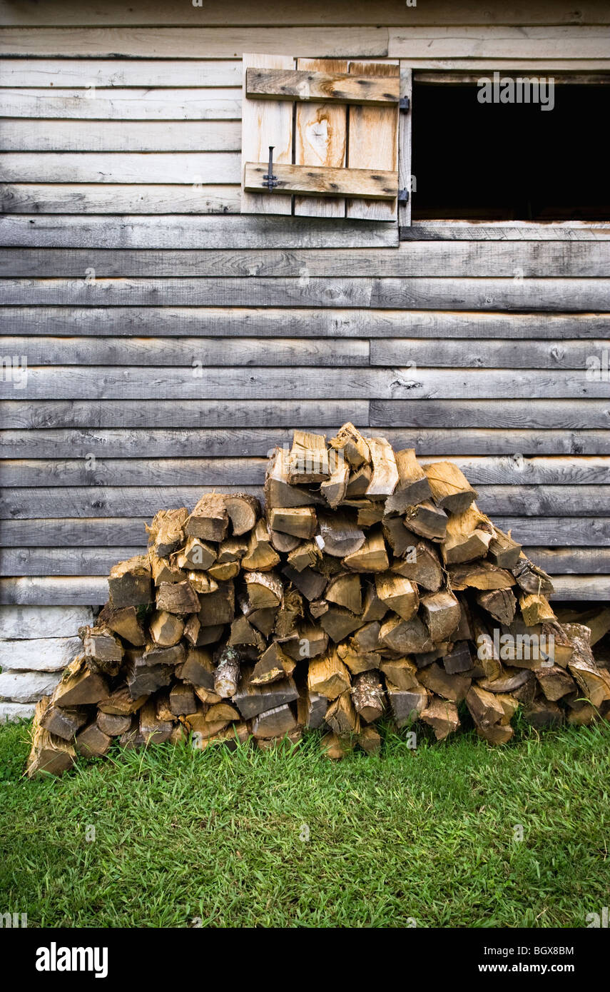 Un montón de madera cortada se encuentra fuera de un hogar los primeros colonos. Foto de stock