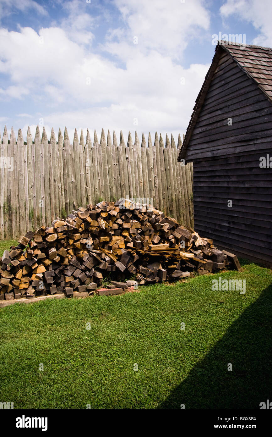 Un montón de madera cortada se encuentra fuera de un hogar los primeros colonos. Foto de stock