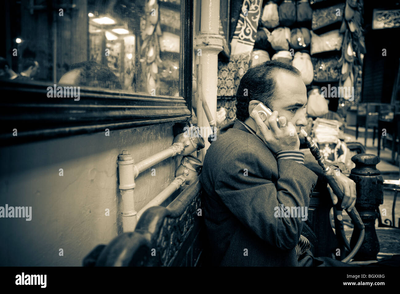 El hombre fumar un tubo hooka en el café mientras el teléfono celular Foto de stock