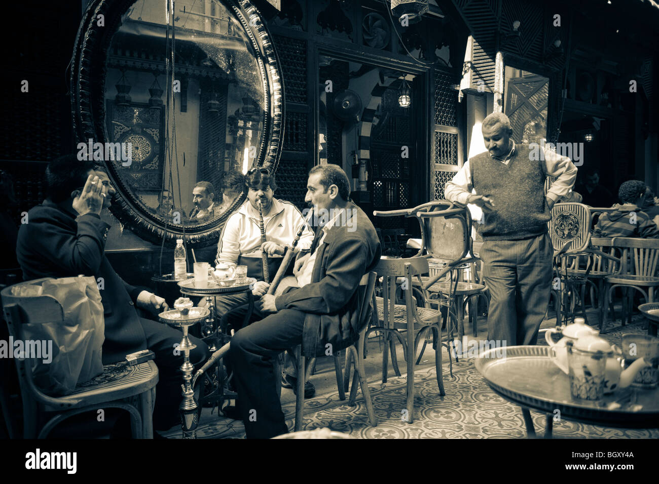 Los hombres fumadores hooka un tubo en una cafetería Foto de stock