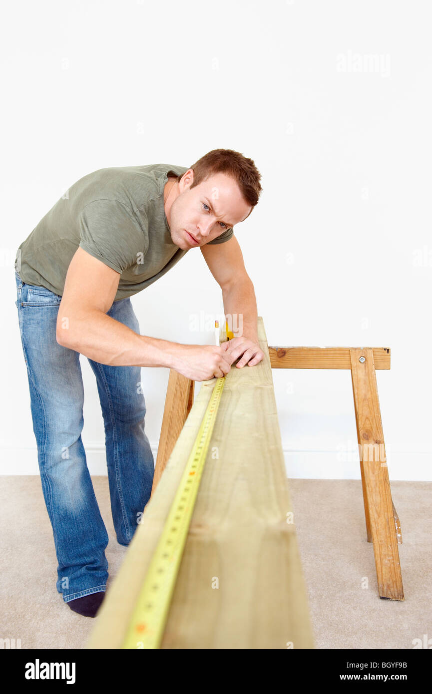 El hombre la medición de plancha de madera. Foto de stock