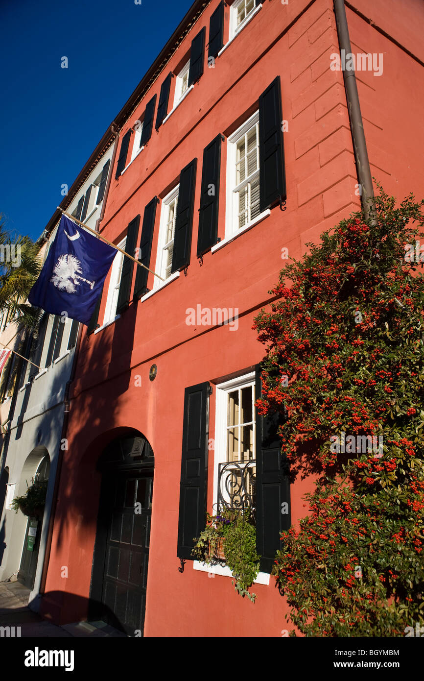 Fila de color rosa con la casa del estado de Carolina del Sur el palmito y luna bandera colgada desde la ventana del segundo piso Charleston Foto de stock