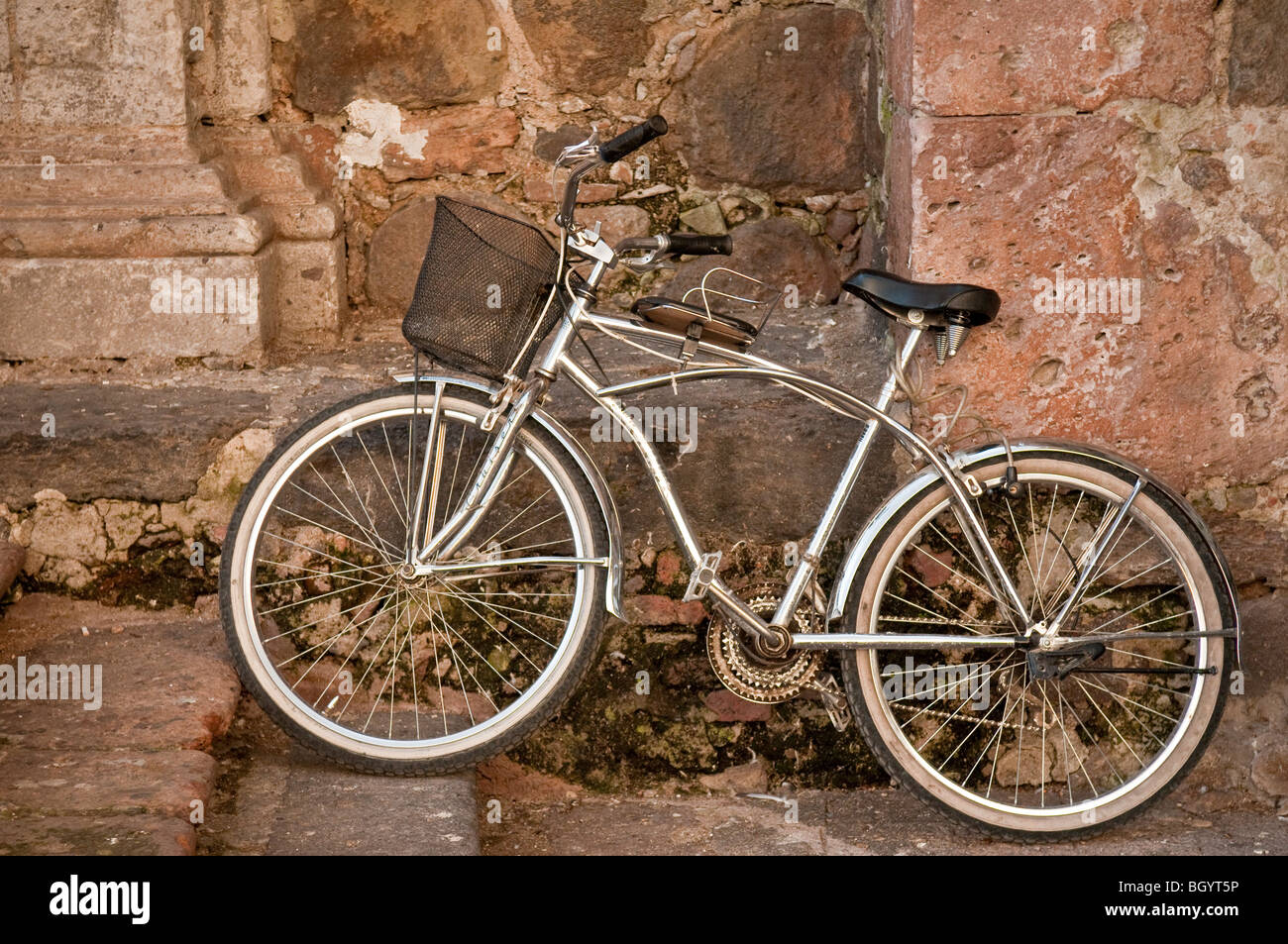 Cromo bicicleta contra la pared de roca de la iglesia en el pueblo de Tequila, Jalisco, México. Foto de stock