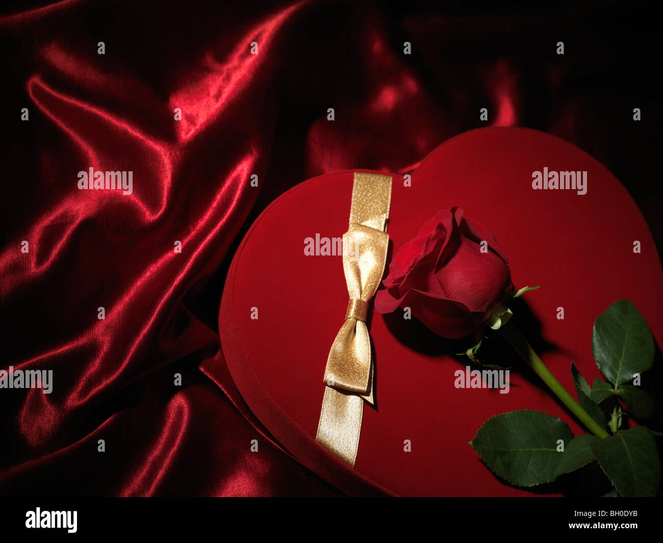 Corazón rojo con forma de caja de regalo y una rosa roja Foto de stock