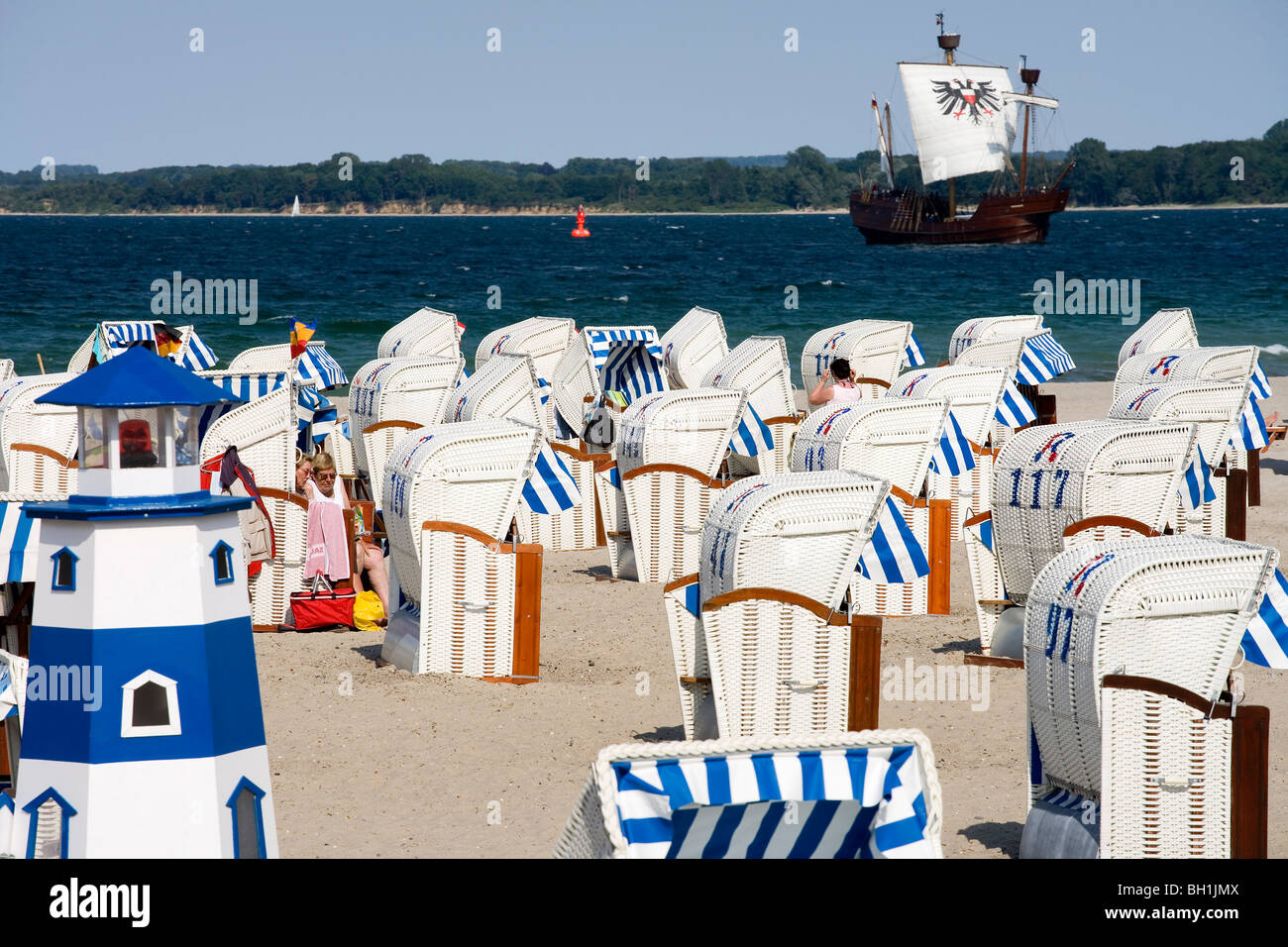 Personas y sillas de playa en la playa, un barco en el fondo, Travemuende, Schleswig Holstein, Alemania, Europa Foto de stock