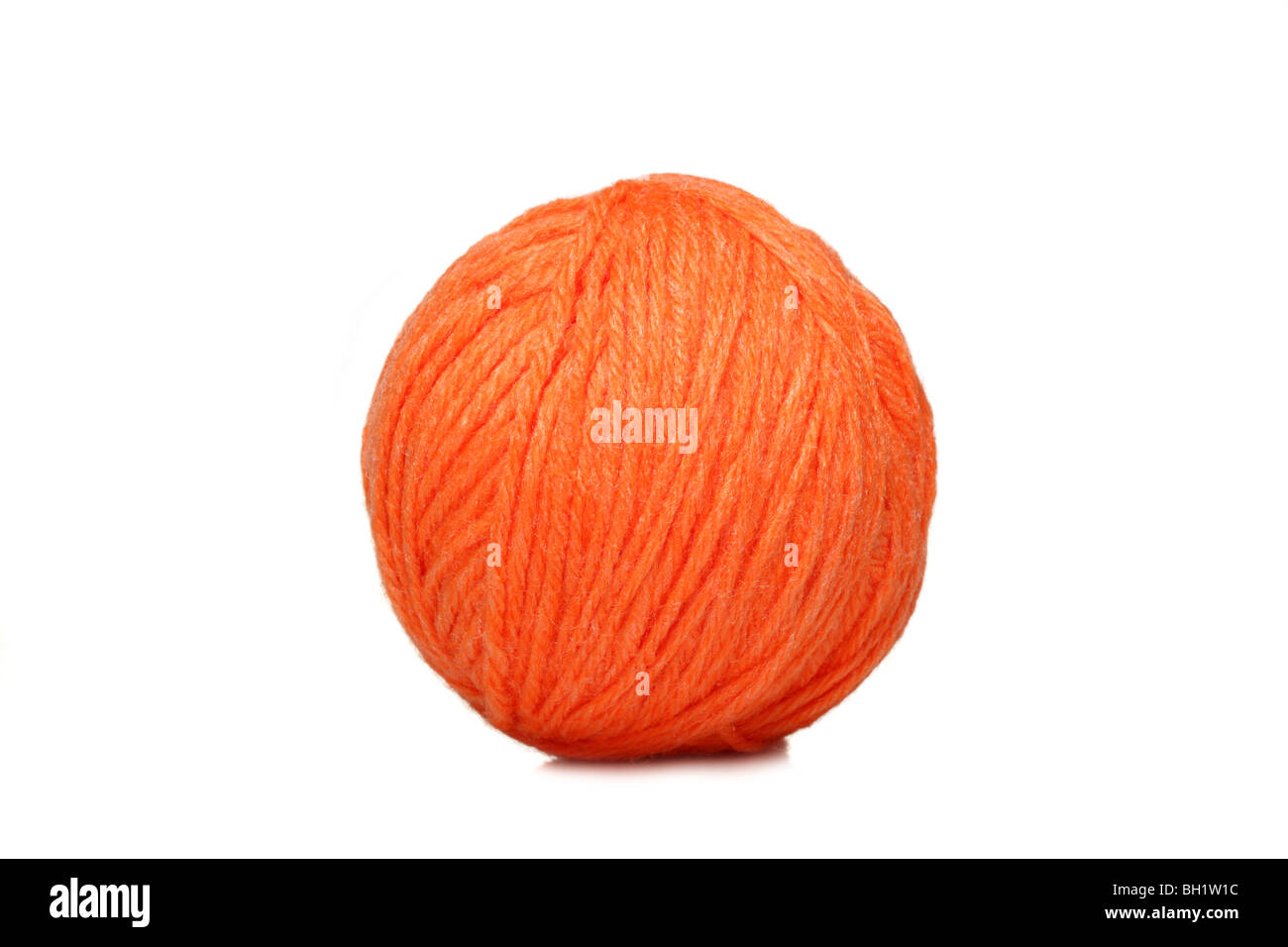 Bola de hilo naranja sobre fondo blanco. Foto de stock