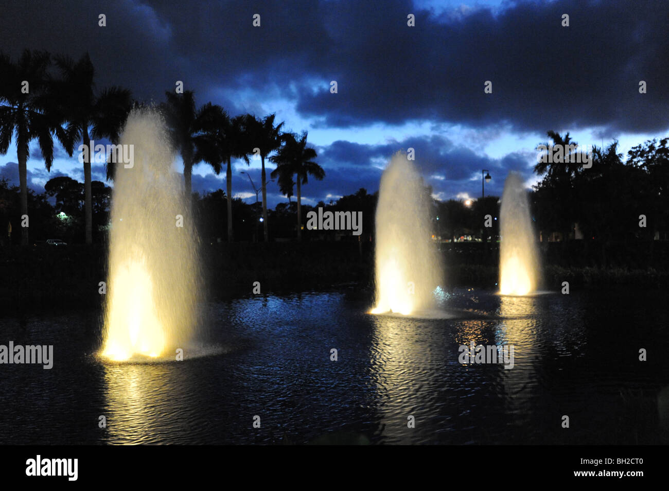 3 fuentes de agua por la noche en el lago, en el Waterside Shops Naples, Florida USA Foto de stock