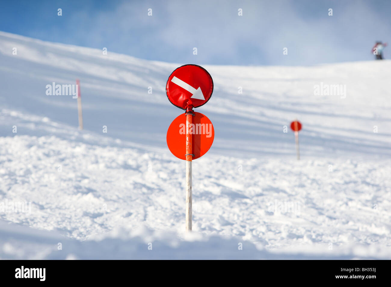 Signo rojo en un post marcando el borde de la pista de esquí con una flecha indicando el camino durante el invierno. Foto de stock