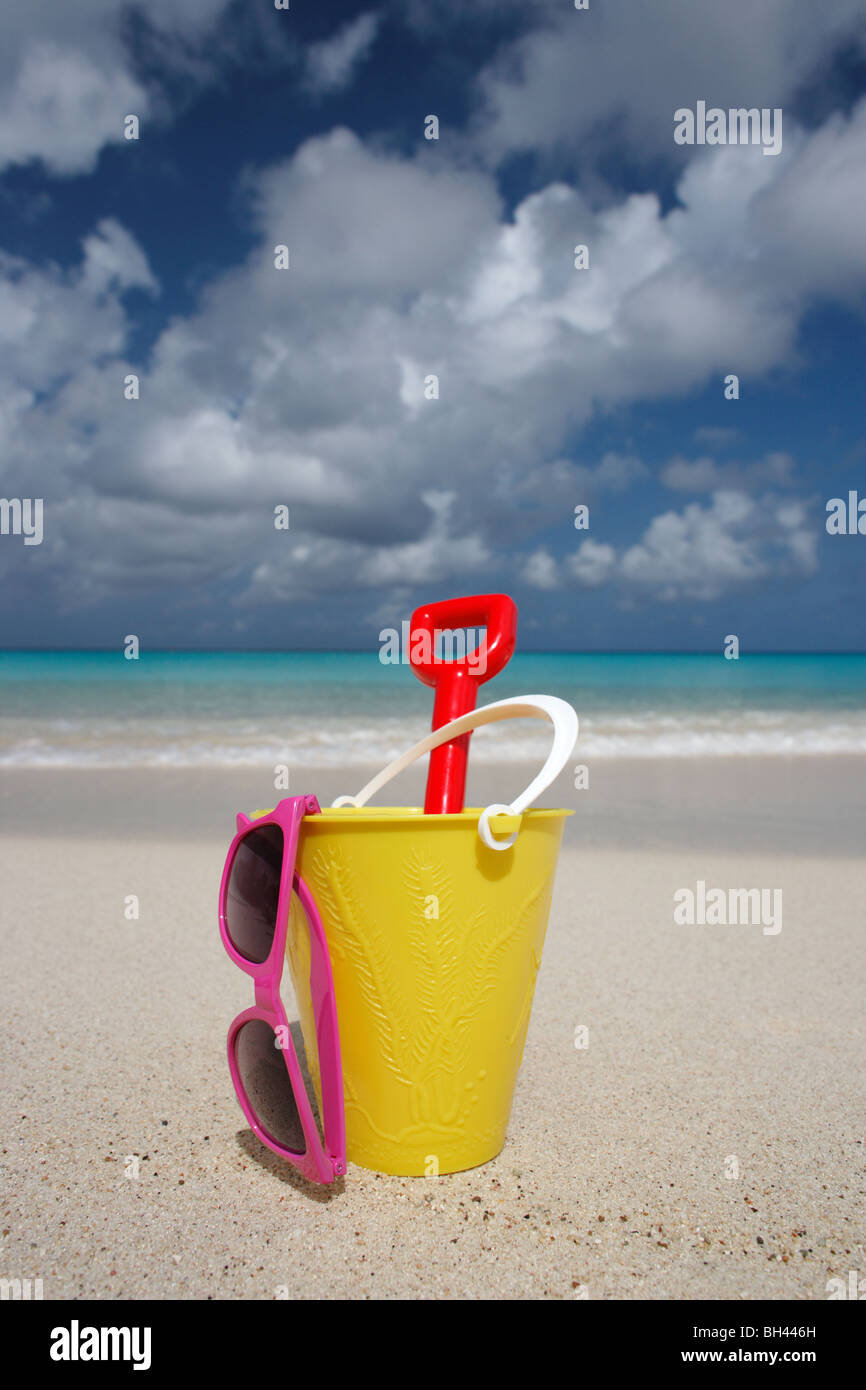 Un cubo amarillo, una pala y un par de gafas de sol en una playa desierta  Fotografía de stock - Alamy