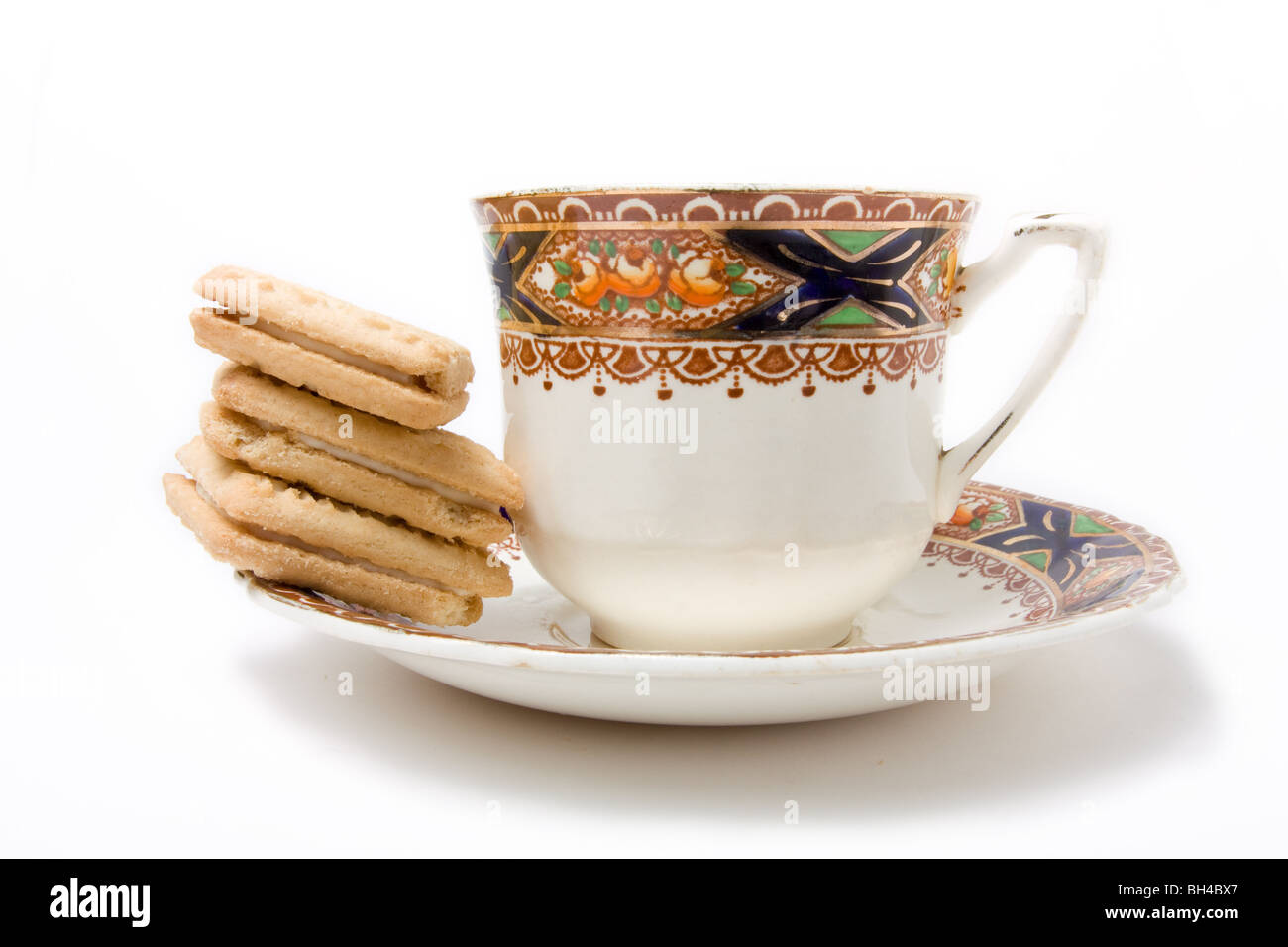 Taza y plato de té con pila de flan galletas crema aisladas contra un fondo blanco. Foto de stock