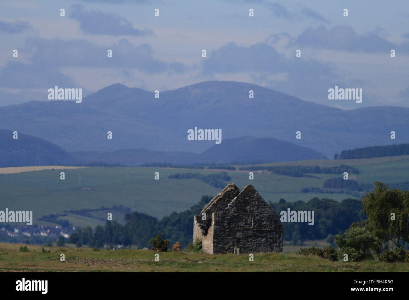 Abandonded cottage en Cromarty Firth con campos y montañas en el fondo. Foto de stock