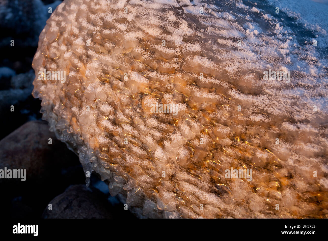 Rocas cubiertas de hielo a orillas del mar al atardecer Foto de stock