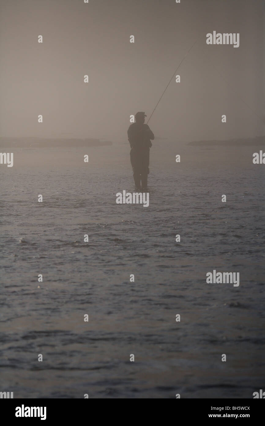 Silueta pescador con mosca Pesca en río de niebla pesada MAL TIEMPO Foto de stock