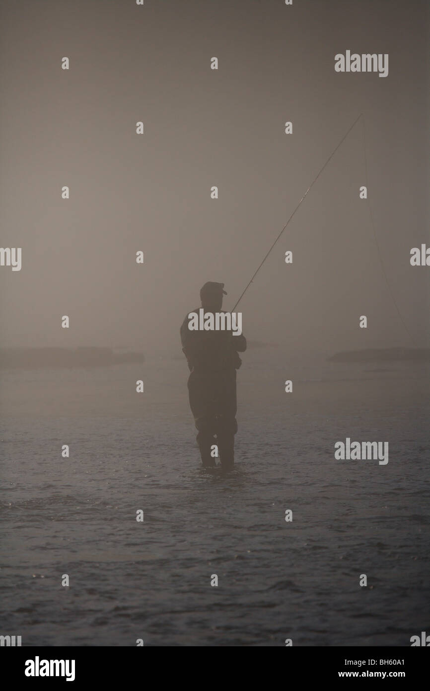 Silueta pescador con mosca Pesca en río de niebla pesada MAL TIEMPO Foto de stock