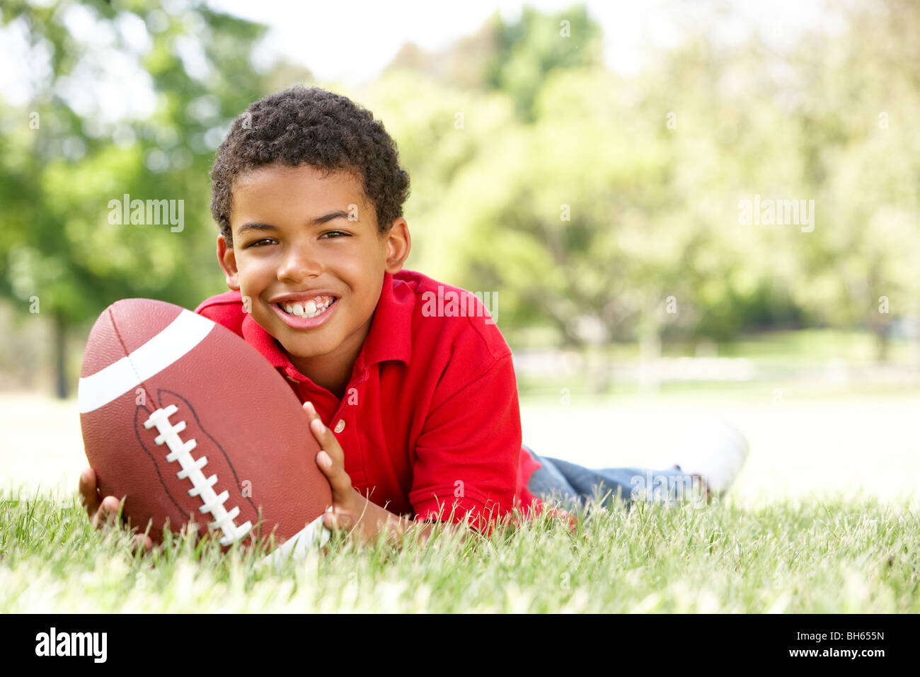 Chico en el parque con el fútbol americano Foto de stock