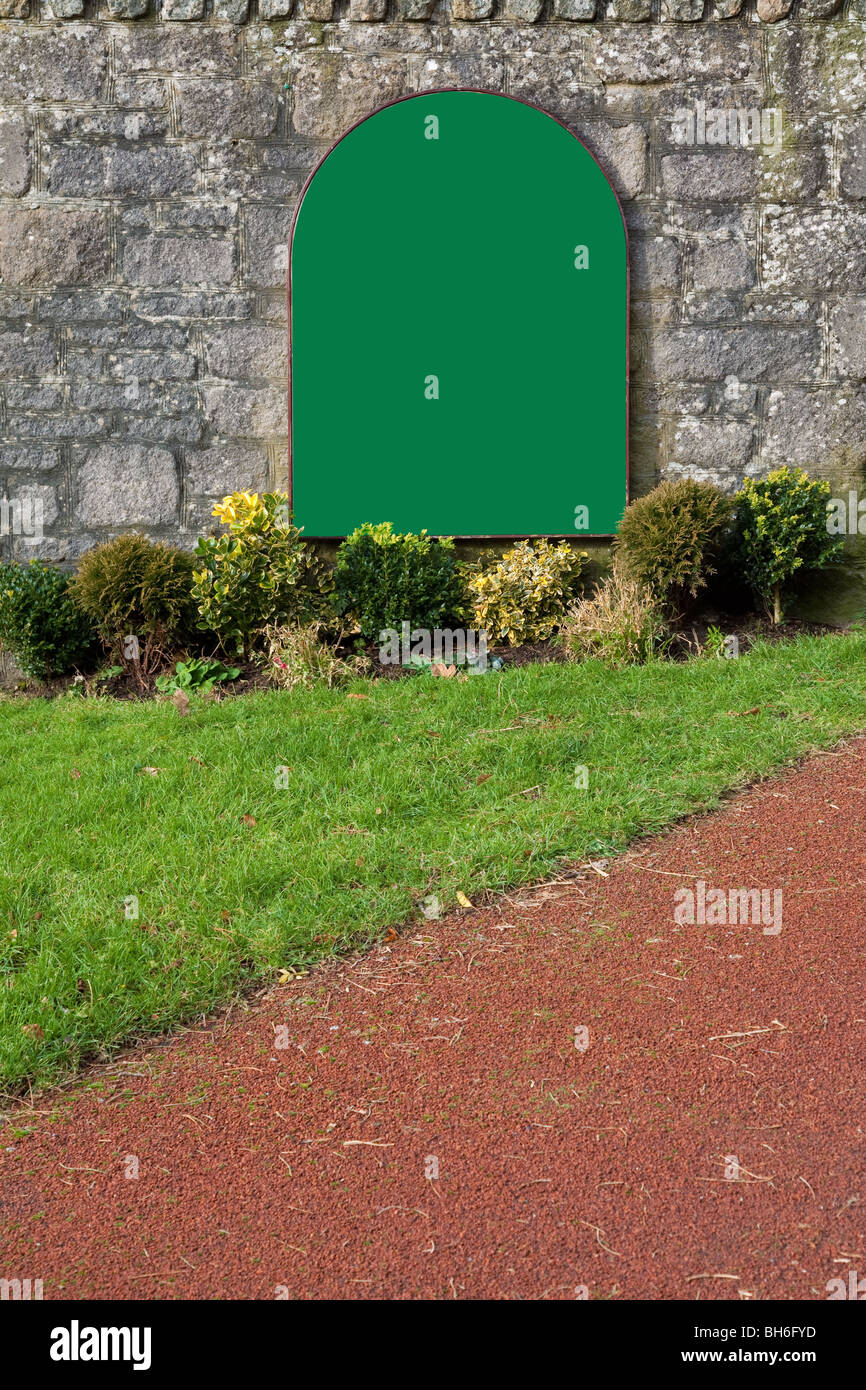 Señal verde blanco sobre un antiguo muro de piedra, agregue su propio mensaje. Foto de stock