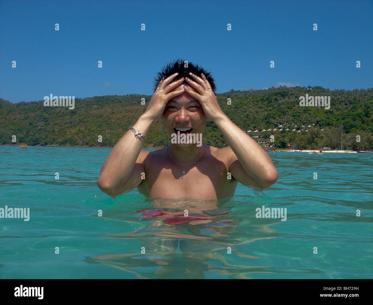 Playa de Phuket, Tailandia, Asia Hombre de pie en el agua sujetando la cabeza, océano en Playa Foto de stock