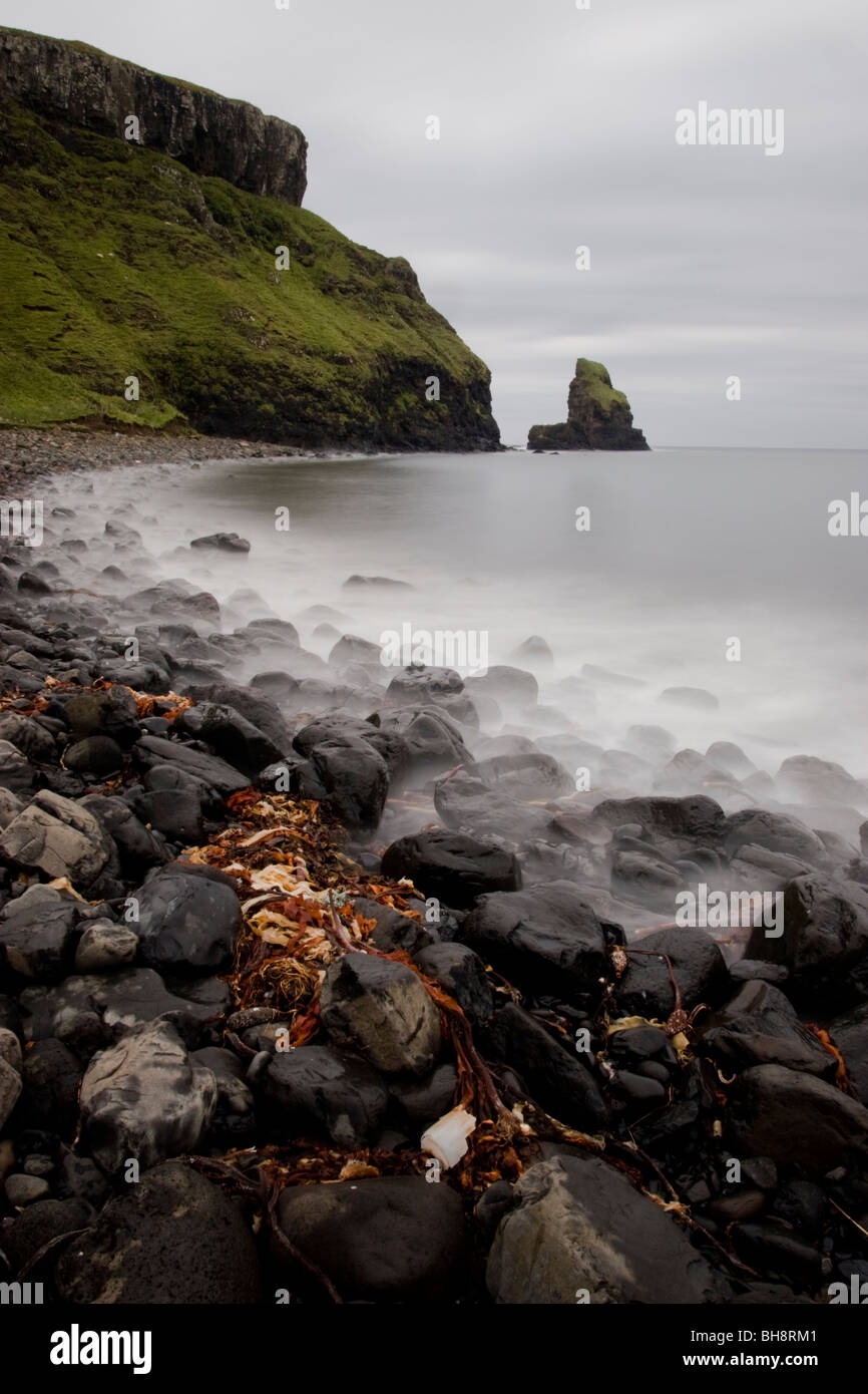 La larga exposición de las olas rompiendo en la playa rocosa al pie de los acantilados de la Bahía de Talisker, Skye, Escocia Foto de stock