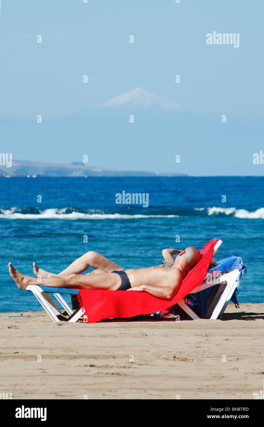 Par tomar el sol en la playa de Las Canteras en Las Palmas de Gran Canaria  con el nevado Teide en Tenerife en la distancia Fotografía de stock - Alamy