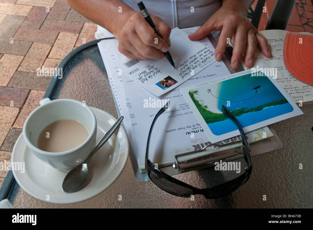 Mujer escribir postales de vacaciones en la playa de Airlie en Queensland Foto de stock